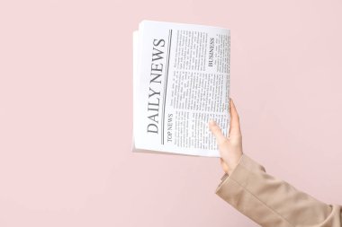 Pembe arka planda günlük gazetesi olan bir kadın.