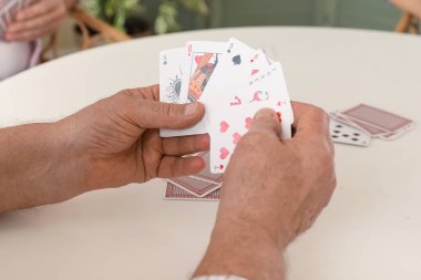 Yaşlı adam evde kağıt oynuyor, yakın plan.