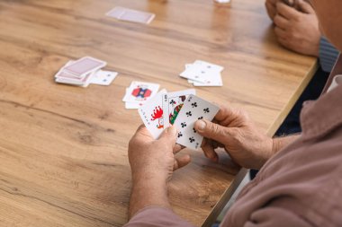 Yaşlı adam evde kağıt oynuyor, yakın plan.