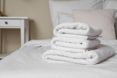 Odadaki yatakta temiz havlu yığını, yakın plan.