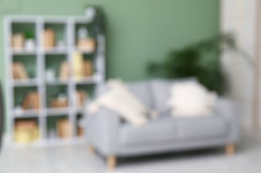 Yeşil duvarın yanında kanepesi ve kitaplığı olan modern oturma odasının içi bulanık.