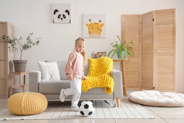 Evde futbol topuyla oynayan tatlı küçük kız.