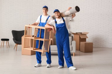 Yükleyiciler taşınma gününde evde raf ünitesi ve halı taşıyorlar.