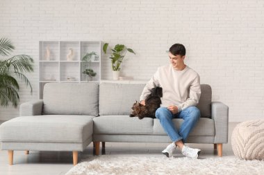 Evdeki kanepede oturan sevimli kedili genç adam.