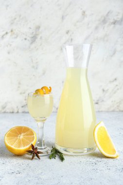 Beyaz arka planda biberiyeli bir sürahi ve bir bardak lezzetli limoncello.