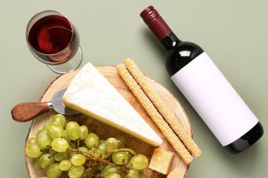 Lezzetli peynir, Grissini, üzüm, şişe ve şarap yeşil arka planda.