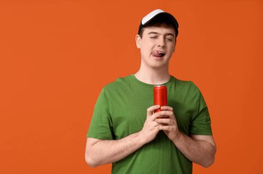 Sodalı genç adam turuncu arka planda dilini gösteriyor.