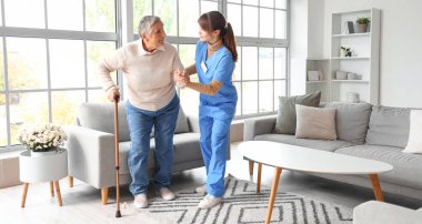 Genç bakıcı, yaşlı kadının eve yürümesine yardım ediyor.