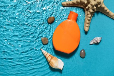 Deniz yıldızlı güneş kremi ve deniz kabukları renkli arka planda.