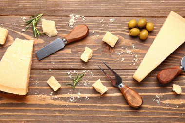 Ahşap zemin üzerinde lezzetli parmesan peyniri, bıçak ve çatal parçaları olan kompozisyon