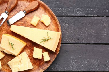 Koyu ahşap arka planda lezzetli parmesan peyniri parçaları ile tabak.