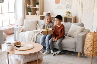 Evdeki kanepede oturan örgü kazaklı şirin çocuklar.