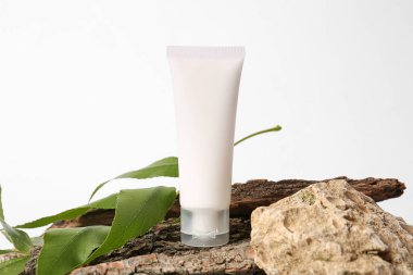 Hafif arkaplanda kozmetik ürün, ağaç kabuğu ve bitki yaprağı tübü ile bileşim