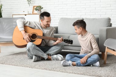 Babası ve küçük oğlu evde gitar çalıyorlar.
