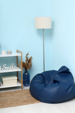 İçinde fasulye koltuğu, yer lambası ve raf ünitesi olan modern oturma odası.