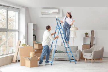 Mutlu genç çift taşınma gününde tavan lambasını çıkarıyor.