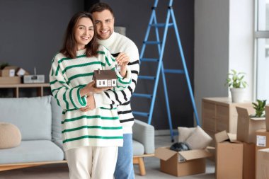 Taşınırken anahtarı ve ev modeli olan mutlu genç bir çift.