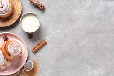 Gri grunge arka planda çörekler, krema ve tarçın çubukları ile tabak