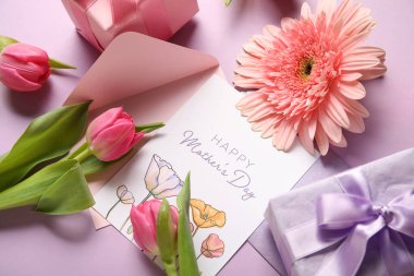 İçinde şenlikli kartpostal, hediye kutuları ve leylak arkaplanda çiçekler olan bir zarf. Anneler Günün kutlu olsun.