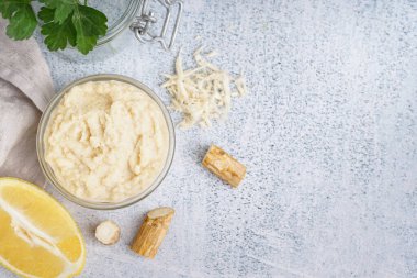 Limonlu cam kasede yabanturpu sosu ve beyaz arka planda yabanturpu kökü. Üst görünüm