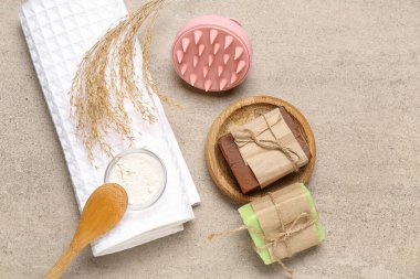 Saç derisi masaj aleti, şampuan çubukları ve grunge grisi arka planda havlu.