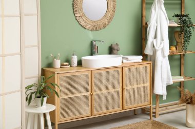 Banyoda yeşil duvarın yanında banyo malzemeleri olan modern lavabo.