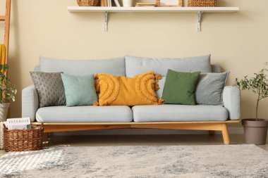 Rahat kanepesi, yastıkları, çiçekleri ve rafları olan modern bir oturma odası.