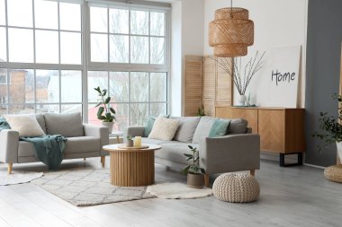 Şık oturma odasının içinde kanepeler ve vazoda söğüt dalları var.