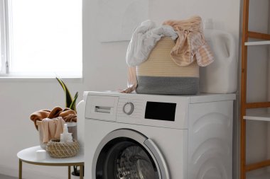 Çamaşır ve deterjanı banyoda olan modern çamaşır makinesi.