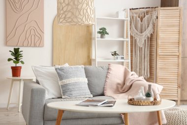 Şık oturma odasının içinde kanepe, yastık, raf ünitesi ve kahve masası var.