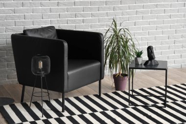 Modern oturma odasının içinde siyah koltuk, masa ve palmiye ağaçları var.