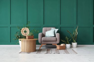 Koltuk, kahve masası ve yeşil duvarın yanındaki bitkiler.