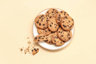 Bej arka planda çikolata parçalı bir tabak tatlı kurabiye.