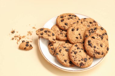 Bej arka planda çikolata parçalı bir tabak tatlı kurabiye.