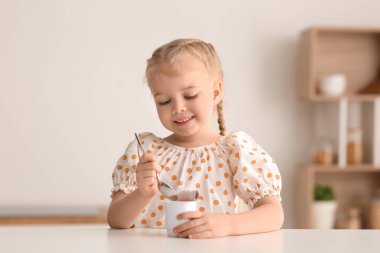Evinde yoğurt ve kaşıkla mutlu küçük kız.