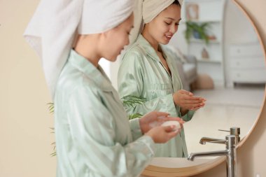 Banyoda lavabonun yanında sabunu olan genç bir Asyalı kadın.