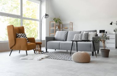 Gri kanepeli, masalı ve koltuklu aydınlık oturma odasının içi.