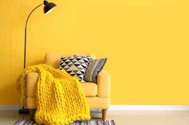 Sarı duvarın yanında battaniyeli koltuk ve yastık yığını