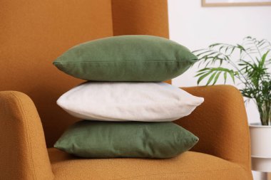 Beyaz duvarın yanında yastık yığını olan rahat koltuk, yakın plan.