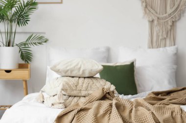 Yatak odasının içinde yumuşak yastıklı ve buruşuk battaniyeli rahat bir yatak.