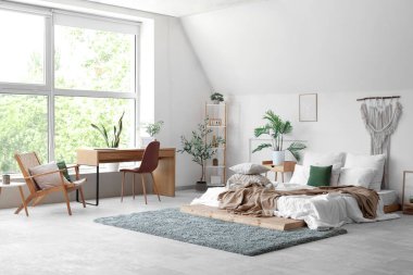 Yatak odasının içinde yumuşak yastıklı ve buruşuk battaniyeli rahat bir yatak.