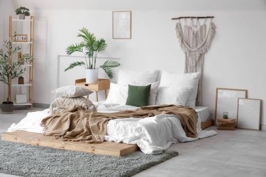 Yatak odasının içinde yumuşak yastıklı ve buruşuk battaniyeli rahat bir yatak.