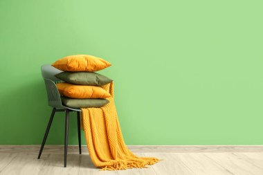 Yeşil duvarın yanında yastık yığını olan sandalye