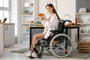 Evinde lezzetli waffle 'ları olan tekerlekli sandalyedeki genç kadın.