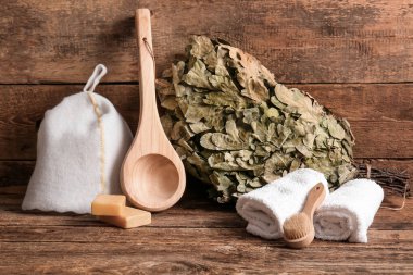 Sauna için farklı aksesuarlar ve ahşap arka planda meşe süpürgesi.