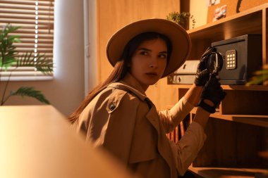 Büyüteci olan bir kadın casus gece ofiste kasayı açıyor.