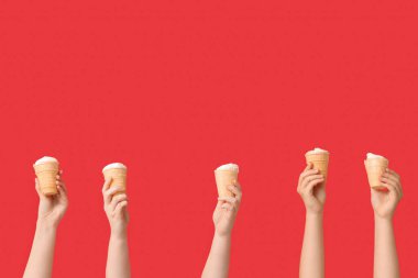 Kırmızı arka planda waffle bardaklarında tatlı dondurmalı kadın elleri