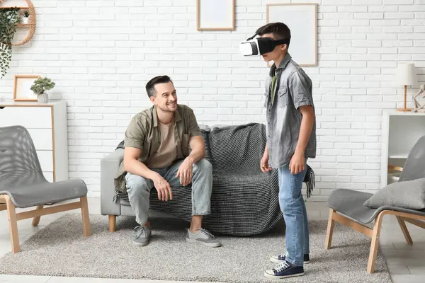 Babası ve VR gözlüklü küçük oğlu evde eğleniyorlar.