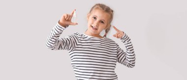 Little girl with eye drops on light background