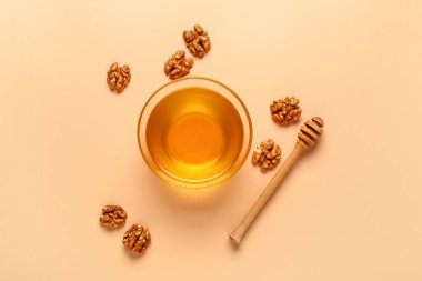 Bej arka planda ceviz ve dipli bir kase tatlı bal.